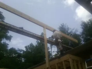 Carpenter setting a ridge beam over a new addition frame — Ice Dam Removal by Roofing Brothers in Phelan