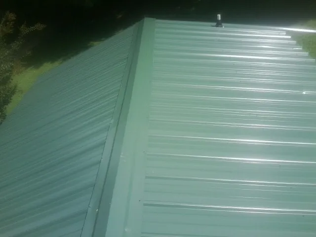 New green metal panels meeting at the ridge of a roof — Flat Roof Repair work by our crew in Phelan