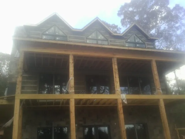 Dormers and porch framing on a large log home under construction — Roof Coating work by our crew in Phelan