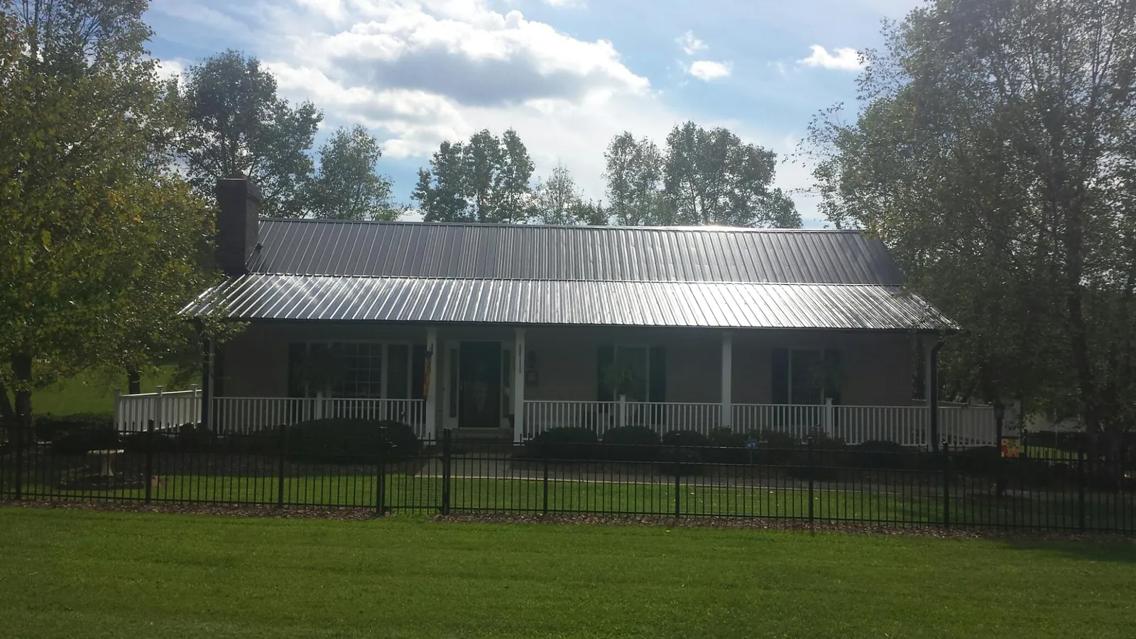 Gray metal roof on a brick ranch with a full width front porch — Gutter Guard Installation work by our crew in Phelan