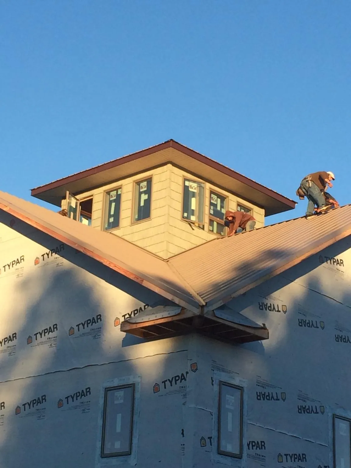 Roofers working around a rooftop cupola on a new metal roof at sunset — Roof Waterproofing in Phelan by Roofing Brothers